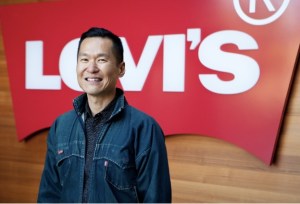 Former Levi Strauss Foundation Executive Director Daniel Lee stands in front of a Levi's sign.